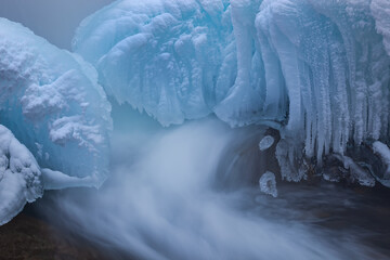 Winter landscape of the Gull Creek cascade framed by ice and captured with motion blur, Michigan, USA
