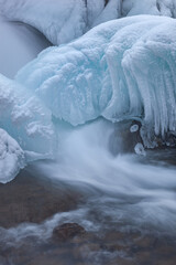 Winter landscape of the Gull Creek cascade framed by ice and captured with motion blur, Michigan, USA
