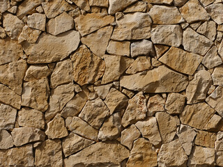 Natural stone wall, the individual stone blocks or rubble stones are connected with mortar, nice background