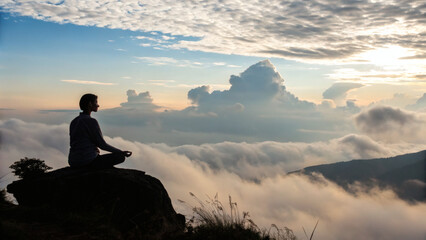 person meditating in silhouette on a mountain