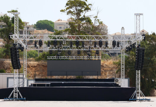Outdoor event stage with a large LED video wall and line array speakers, the truss system provides the necessary stability