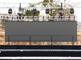 Outdoor event stage with a large LED video wall and line array speakers, the truss system provides...