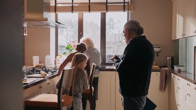Grandfather stands and holds a folder while talking to two granddaughters who are getting out of chairs