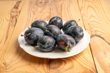 Sweet black plum on a wooden table, close-up.