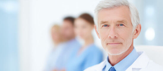 Doctor in focus with a blurred medical team in the background. Professional healthcare teamwork concept, confidence