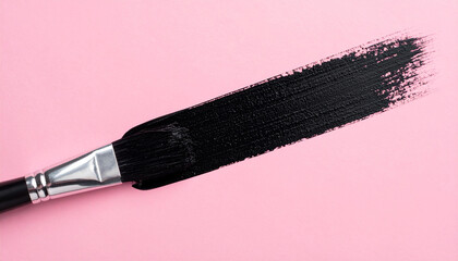 Brush with black paint and brushstroke on pink background. Abstract composition. Top view.