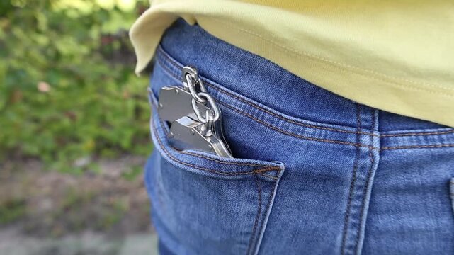 Silver handcuffs tucked into the back pocket of blue jeans