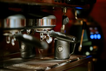 A stainless-steel espresso machine is brewing a fresh cup of coffee at a small cafe early in the morning. Steam rises as the aromatic beverage is prepared for a customer