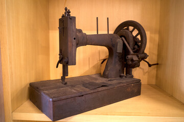 A vintage sewing machine with rustic appearance on the shelf with wooden background