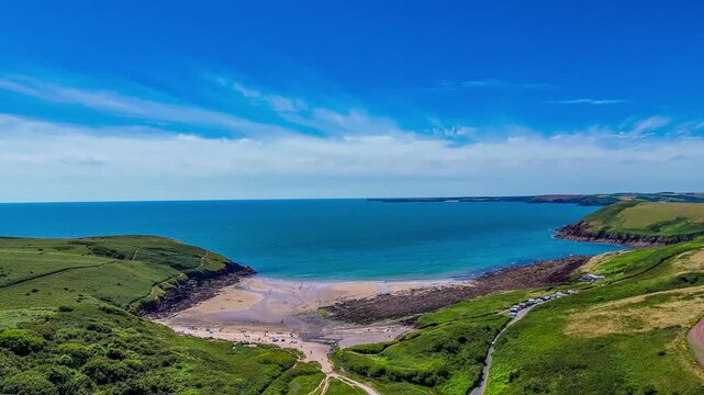 An aerial view panning up and out to, sea from the old Norman castle ruins at the seaside resort of Manorbier, South Wales in summertime