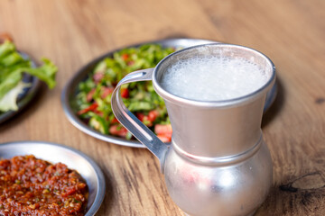 Macro shot of local Turkish ayran in a gray copper glass on a wooden background	
