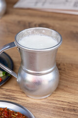 Macro shot of local Turkish ayran in a gray copper glass on a wooden background	