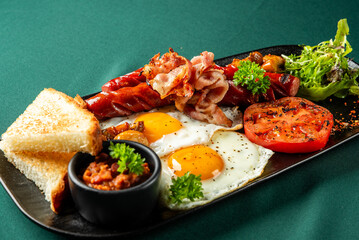Traditional English breakfast with eggs, bacon, sausages, toast, grilled tomato, baked beans, and...