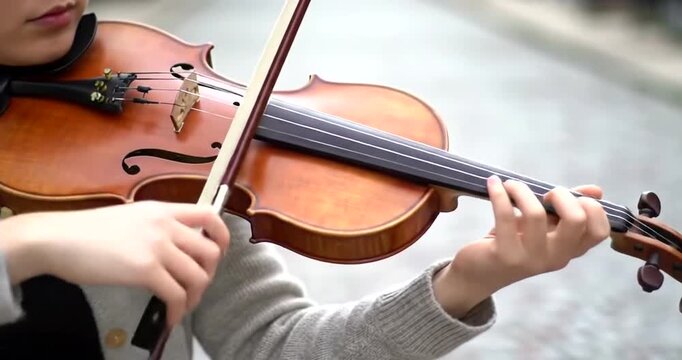 Young woman playing the violin outdoors, practicing classical music with a bow