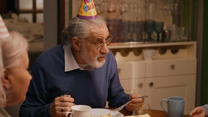 Grandfather talking to grandmother and granddaughter while they sit at the table and eat