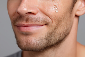 Obraz premium Close up of man lower face with clear serum drop on cheek showing clean skin and subtle smile