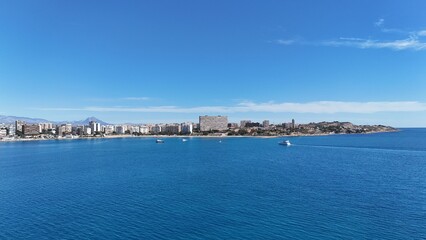 Fototapeta premium Panoramic view of a coastal city with modern buildings, sandy beach and clear blue sea under a bright sunny sky