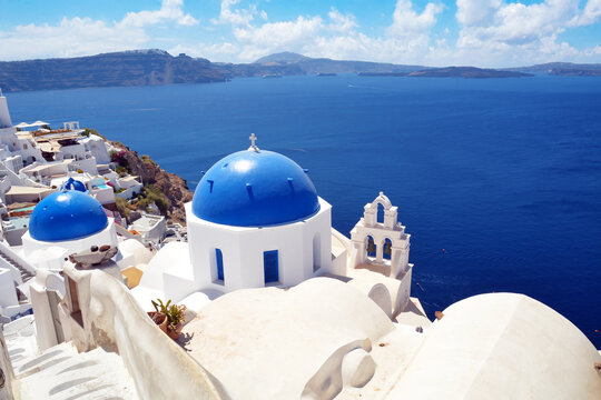 Oia village on Santorini island, Greece. Traditional and famous church with blue domes and white houses over the Caldera, Cyclades islands Aegean sea.
