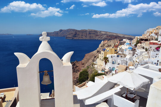 Oia village on Santorini island, Greece. Traditional and famous bell tower with white houses over the Caldera, Cyclades islands Aegean sea.