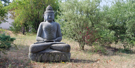 Obraz premium Statue de bouddha dans le jardin, avec arrière plan nature arbre et feuilles