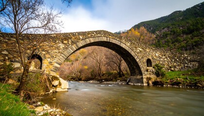 Fototapeta premium Ancient stone arch bridge over a flowing river