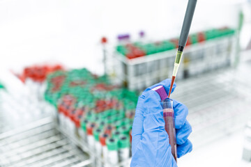 Scientist hand holding pipette drop blood from blood test tube.Health care researchers working in life science laboratory research work for test a vaccine and pharmacy production of medicines test.