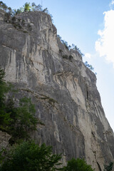 towering vertical rock face, featuring stunning geological formations and textures under a clear summer sky, perfect for depicting adventure, nature, and the great outdoors
