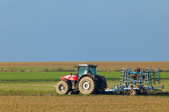 Red tractor plowing a field under blue sky