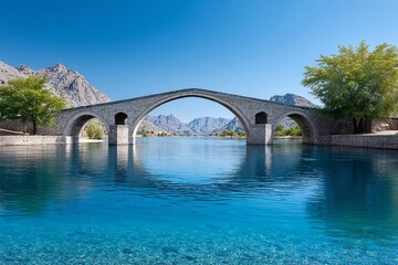 Fototapeta premium A serene stone bridge reflected in the calm blue water.