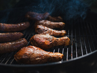 Side low view if chicken and sausages on a grill with smoke 