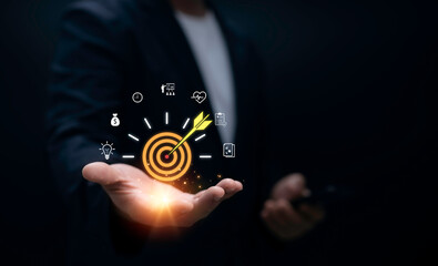 Businessman holding digital target icon with arrow in bullseye surrounded by business strategy finance innovation and success symbols for corporate goal achievement and marketing concept