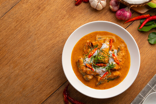 Canned Mackerel fish with red curry sauce topped with shredded kaffir lime leaves and chilli,Thai Chu Chee Fish Curry with coconut milk in white plate.Top view copy space.