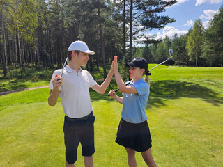 Golfers celebrate a successful shot on a sunny day at a green course