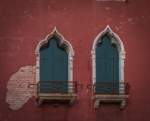 Traditional Venetian windows with green shutters and balconies