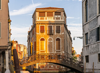 Venetian canal with footbridge and boats at sunset