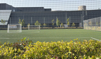 Spacious urban playground featuring a soccer field and colorful play structures on a sunny day in...