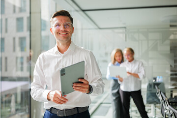 Business professional smiles confidently while colleagues collaborate in modern office environment during productive teamwork