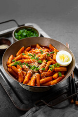 Korean street food, tteokbokki with egg and sesame on dark table vertical photo