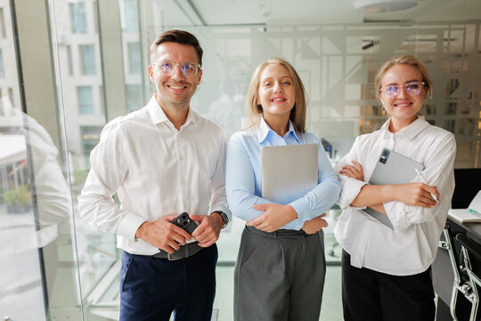 Team of professionals confidently collaborating in a modern office setting with innovative technology and bright smiles