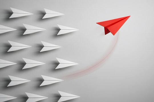 A red paper airplane leading a group of white paper airplanes. 