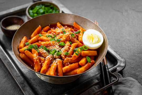 Korean street food, tteokbokki with egg and sesame on dark table
