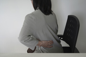 An asian businesswoman overworks and feels pain in her neck from using a laptop, hand holding and...