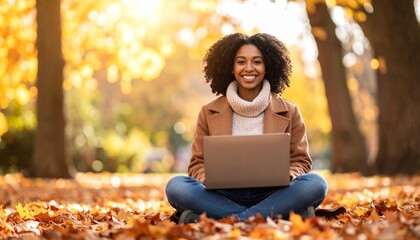 Smiling Woman Working Outdoors with Laptop amid Autumn Foliage in Golden Light