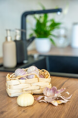 Basket with Chinese single clove garlic and one peeled garlic clove on kitchen countertop. Cooking preparation, fresh ingredient, and natural seasoning.