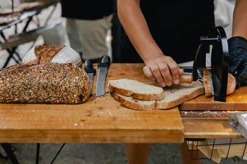 Hand-slicing craft bread on a table in a local Portuguese bakery. The healthy eating and traditional bakery concept. Close up. Part of the series