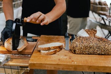 Hand-slicing craft bread on a table in a local Portuguese bakery. The healthy eating and traditional bakery concept. Close up. Part of the series