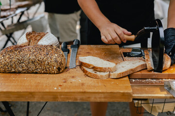 Hand-slicing craft bread on a table in a local Portuguese bakery. The healthy eating and traditional bakery concept. Close up. Part of the series