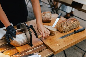 Hand-slicing craft bread on a table in a local Portuguese bakery. The healthy eating and traditional bakery concept. Close up. Part of the series