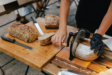 Hand-slicing craft bread on a table in a local Portuguese bakery. The healthy eating and traditional bakery concept. Close up. Part of the series