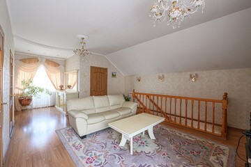cozy living room featuring a beige sofa, patterned rug, wooden banister, and chandelier lighting